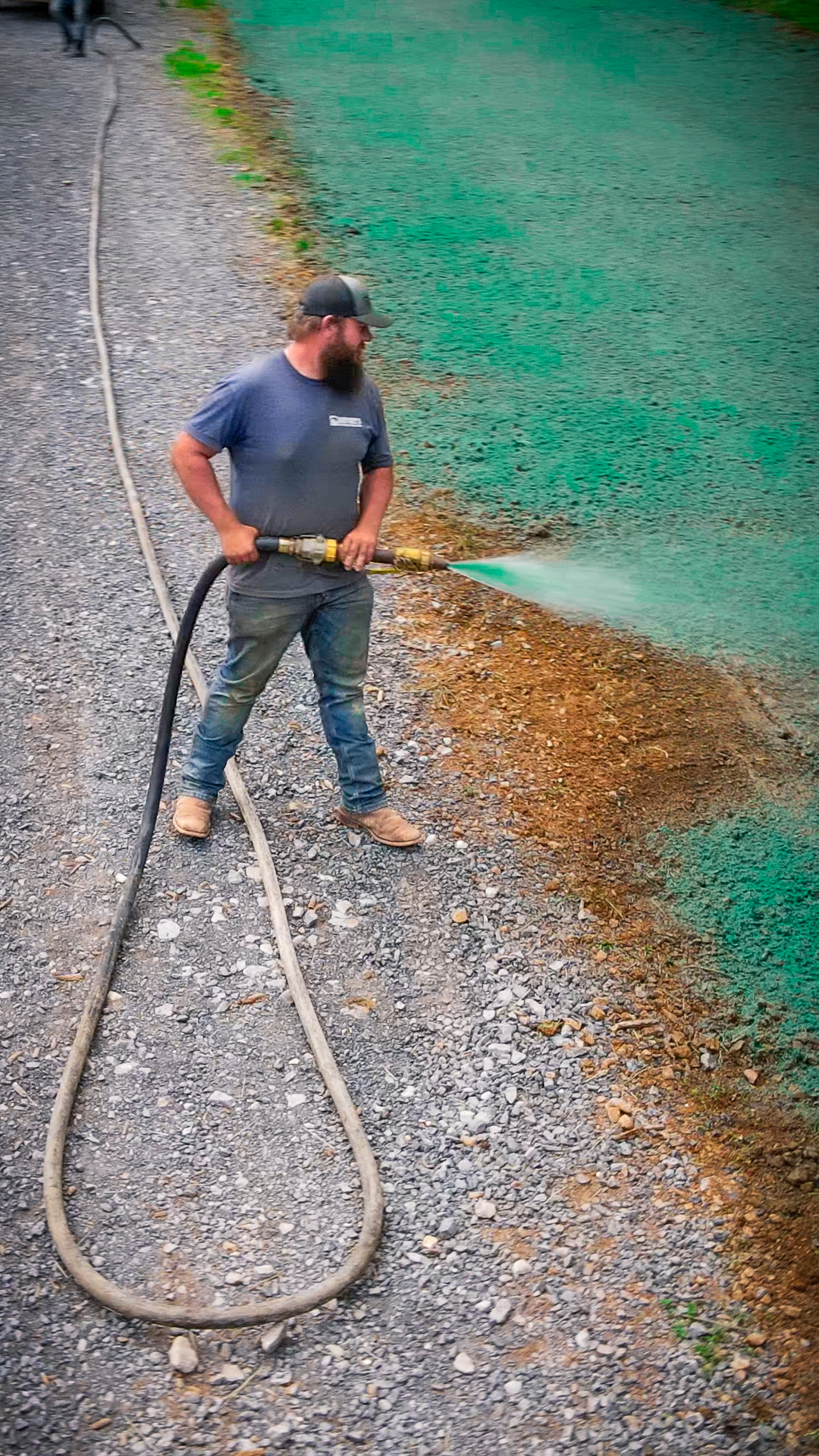 man spraying hydroseed fertilizer application on dirt yard to grow grass